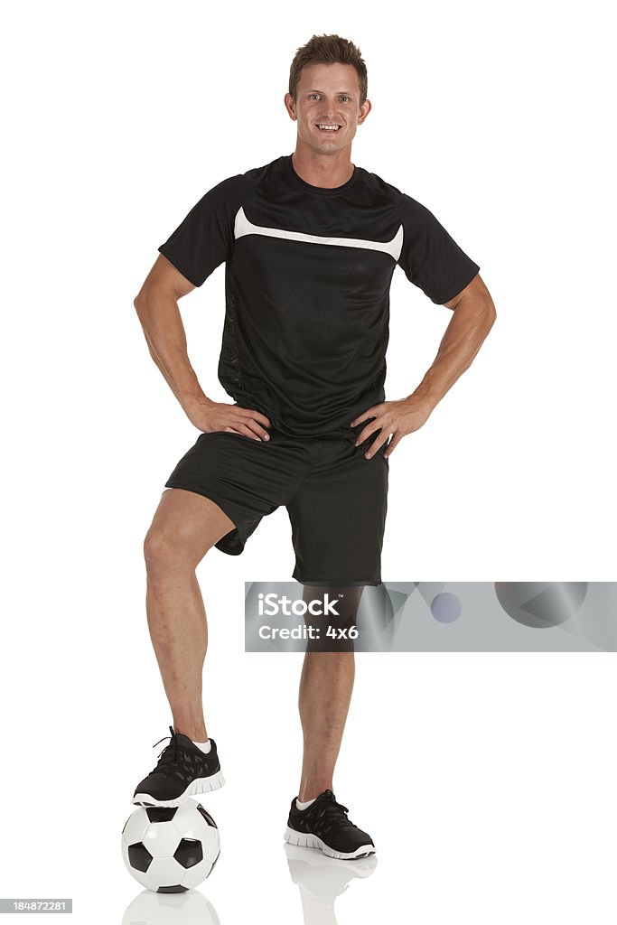 Hombre de pie con sus un pie en una pelota de fútbol - Foto de stock de Jugador de fútbol libre de derechos