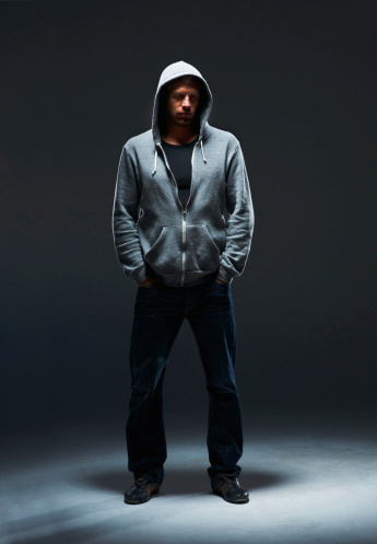 Portrait of smart looking man wearing hooded sweatshirt with hands in pockets