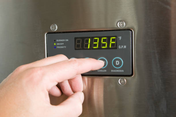 Male Finger Turning Down Tankless Water Heater Temperature stock photo