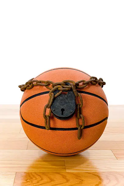 Concept-NBA Lockout. Basketball sitting on hardwood court with a chain and padlock