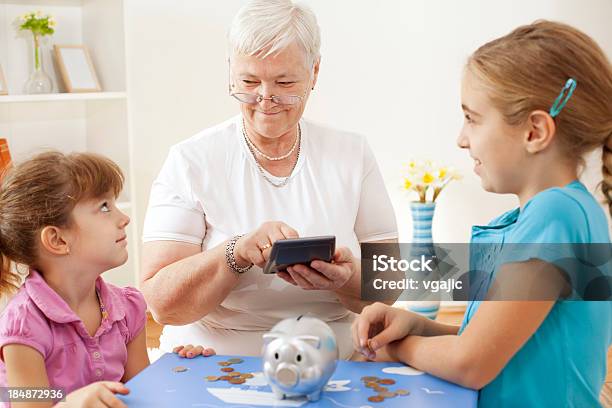 Foto de Avó Com Seus Netos Contando Dinheiro No Piggy Bank e mais fotos de stock de Avó - Avó, Moeda Corrente, Mulheres Idosas