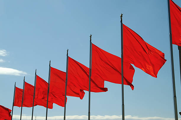 istock Row of red flags on poles blowing in the wind under blue sky 184873053