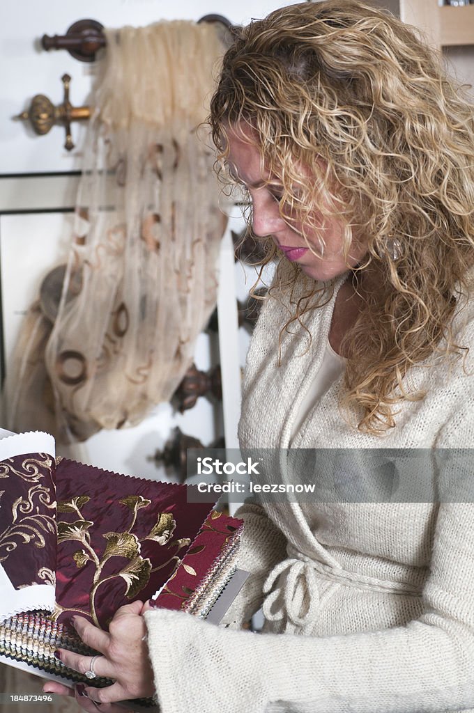 Woman Looking At Fabric Swatches "Closeup of woman shopping at a home furnishings store, looking through drapery fabric samples.  Display of curtain rods in the background.Click below for more in this series, plus all of my furnishings and retail images:" Adult Stock Photo