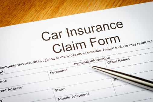 A Car Insurance Claim Form on a desk with Ballpoint pen.