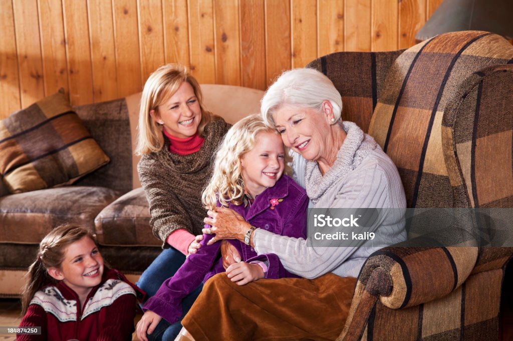 Three generation family in cabin living room Senior woman (60s) with daughter (40s) and grandchildren (7 and 12 years) in living room of cabin.  Main focus on blond girl and grandmother. 12-13 Years Stock Photo