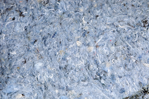 A close-up section of recycled blue jean denim insulation which is a new type containing 80% recycled natural fibers and has no fiberglass itch or irritants. Recycled denim is increasing in popularity as a sustainable and clean alternative to fiberglass.