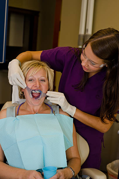 Dental Worker inserting Cheek Retractor for Procedure stock photo
