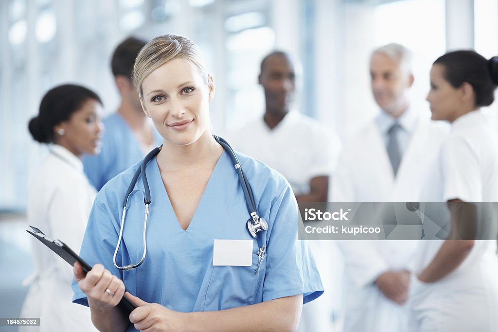 Bella infermiera con il personale medico in sottofondo - Foto stock royalty-free di Persone