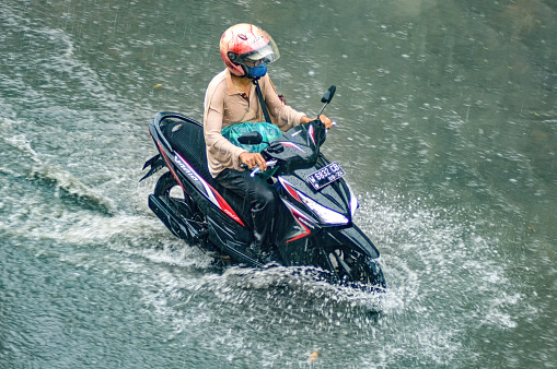 a motorcyclist who drove through flood waters during heavy rain in a residential area, Indonesia, 8 December 2023.