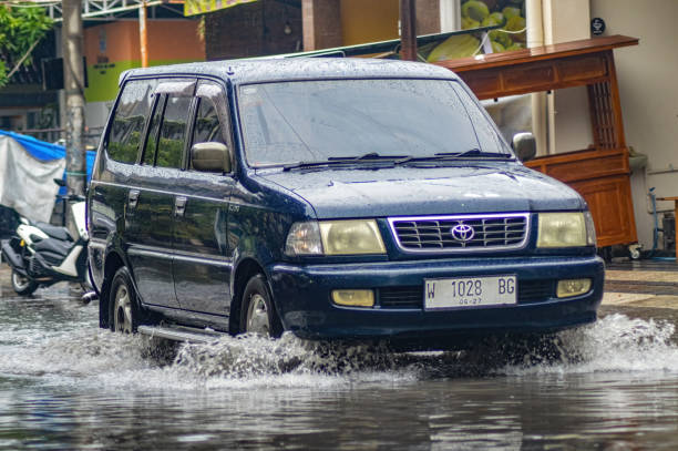 a Toyota Kijang car that broke through floodwater during heavy rain on a residential street a Toyota Kijang car that broke through floodwater during heavy rain on a residential street, Indonesia, 8 December 2023. kijang stock pictures, royalty-free photos & images