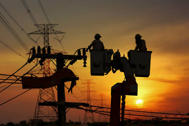 group of silhouette electric worker working on pole connected high voltage transmission line with  high voltage transformer station