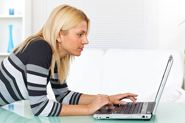 istock Young smiling woman using laptop computer indoors 184876278