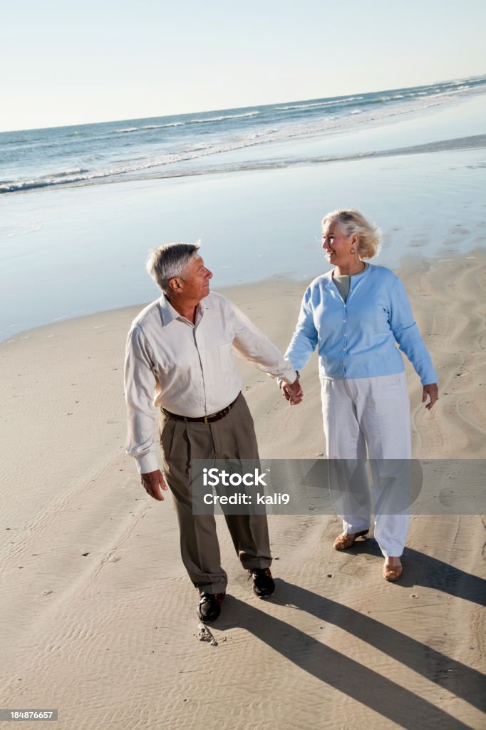 Coppia Senior a piedi sulla spiaggia - Foto stock royalty-free di 60-69 anni