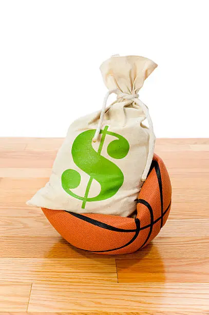 Concept-NBA Lockout. Basketball sitting on hardwood court with a money bag crushing the ball 
