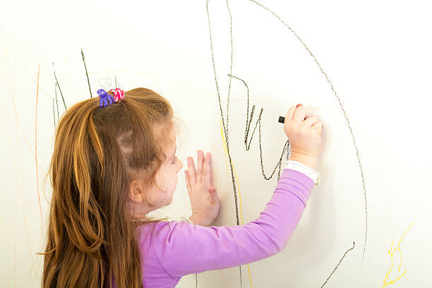 Niña está pintando en la pared - foto de stock