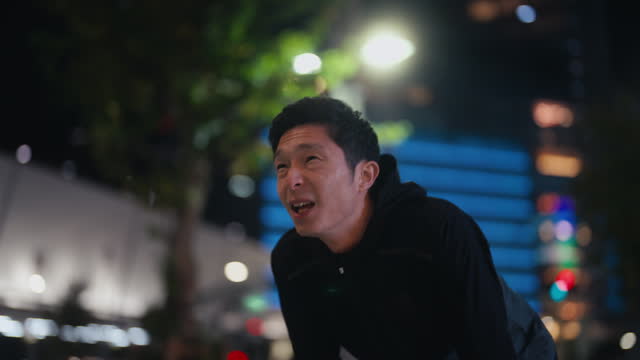 Male Asian athlete running in city at night