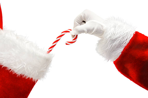 Santa Claus putting a candy cane in a stocking stock photo