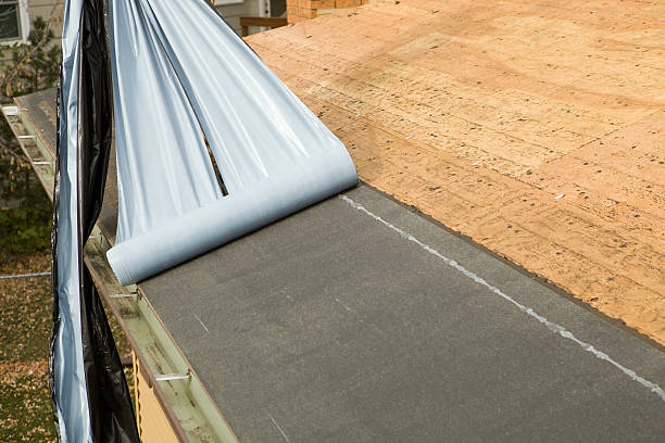 Top view flat roof with air conditioners and hydro insulation membranes on top of a modern apartment building with green football field summer day.