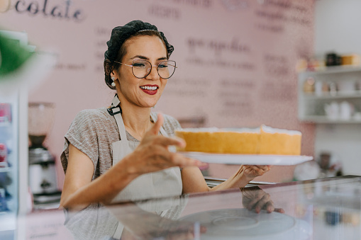 Woman baker placing a cake on the counter