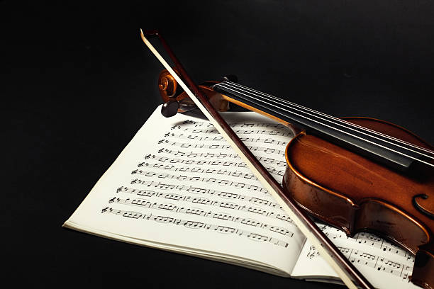 violino e fiocco sulla musica fogli - violin equipment classical instrument light and shadow foto e immagini stock
