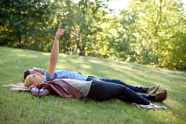 istock Young Couple Lounging in the Grass and Pointing 184880298