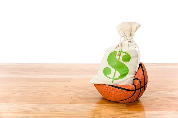 Concept-NBA Lockout. Basketball sitting on hardwood court with a money bag crushing the ball