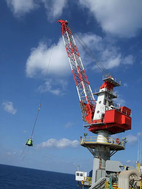 A crane with personnel basket transferring personnel More oilfield images: