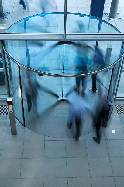 Photo of Business People Walking Through Glass Revolving Door