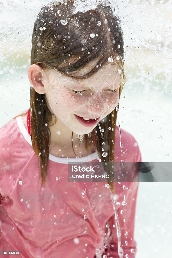 Girl (8) jugando en el parque acuático bajo la cascada de la piscina - Foto de stock de 8-9 años libre de derechos