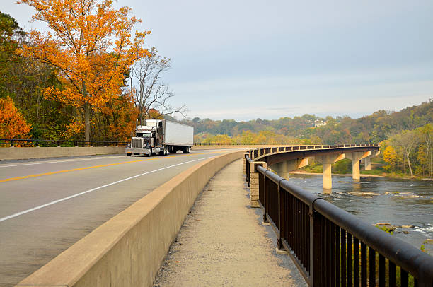Tractor Trailer Crossing Shenandoah River "Properly titled, a tractor trailer crossing the Shenandoah river near Harpers Ferry in West (by God) Virginia with the trees displaying their fall foliage." harpers ferry photos stock pictures, royalty-free photos & images