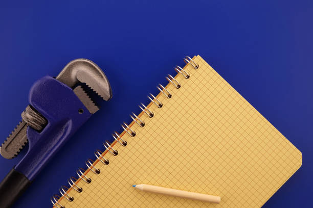 Renovation, building, manufacturing, production or repairs flat lay concept with an arrangement of two assorted wrenches, pencil and note book