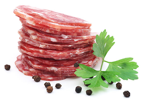 Stacked dry salami with parsley and pepper isolated on white