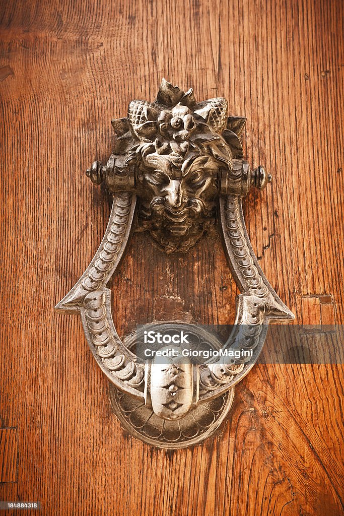 Evil Head Knocker on a Wooden Door Evil head knocker on a wooden door in Florence (Tuscany, Italy). Anthropomorphic Stock Photo