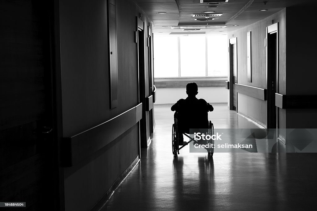 Silhouette di uomo su sedia a rotelle in corridoio scuro - Foto stock royalty-free di Sedia a rotelle