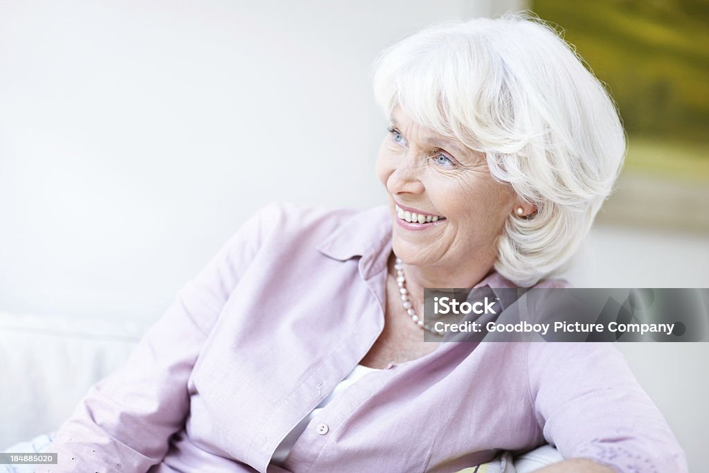 Smiling senior woman on sofa Portrait of happy senior woman smiling while relaxing on couch 60-69 Years Stock Photo