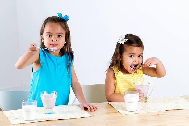 bambina mangiare yogurt - little girls small eating breakfast foto e immagini stock