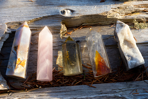 A close up image of 5 beautiful crystal healing towers resting on a weathered piece of driftwood.