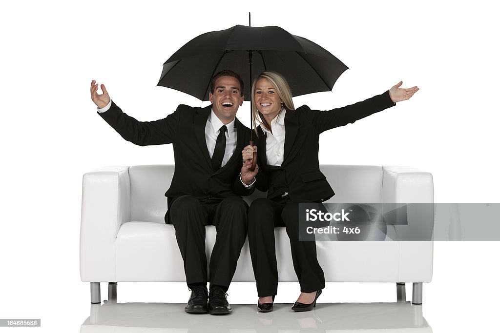 Business couple sitting on a couch under an umbrella Business couple sitting on a couch under an umbrellahttp://www.twodozendesign.info/i/1.png Umbrella Stock Photo
