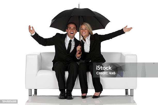 Business Couple Sitting On A Couch Under An Umbrella Stock Photo - Download Image Now