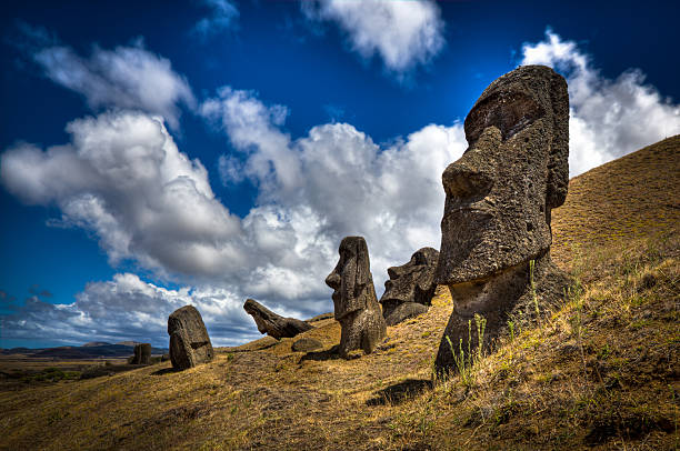 Moais at Rano Raraku Volcano DSLR picture of Moais at the Easter Island in Chile. Moais are human figures carved by the Rapa Nui people in rock. One Moais is in the foreground and four in the background. The sky is mostly sunny with clouds.  moai statue rapa nui stock pictures, royalty-free photos & images