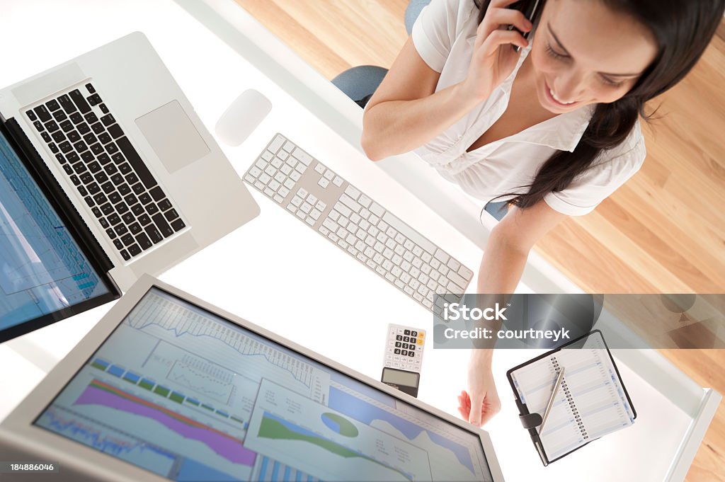 Donna d'affari alla sua scrivania al telefono sorridente - Foto stock royalty-free di Adulto