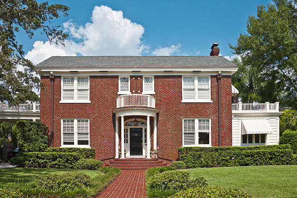 Upscale Brick Home "Federal style colonial home. The entrance to a traditional American home. Includes brick exterior walls, portico,  porte-cochere, Palladian window above the front door, porch, balcony, and expansive front yard." colonial style stock pictures, royalty-free photos & images