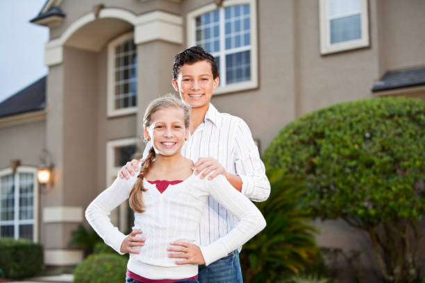 istock Brother and sister standing outside house 184886349