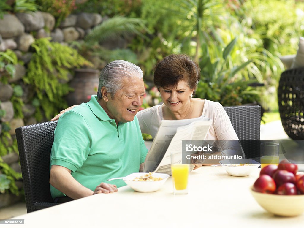 Starsza para czytanie gazety podczas posiłku śniadanie - Zbiór zdjęć royalty-free (60-64 lata)