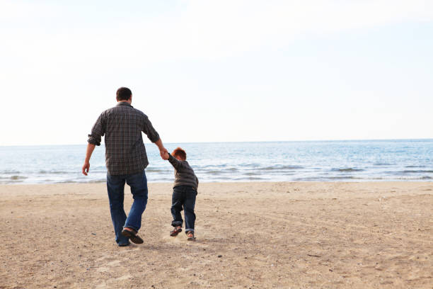 istock Father and son walking hand-in-hand on the sandy beach 184886411