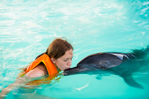 Front view of  young women kissing the dolphin
