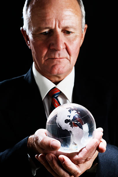 istock Serious businessman looks down at crystal globe contemplating 184886961