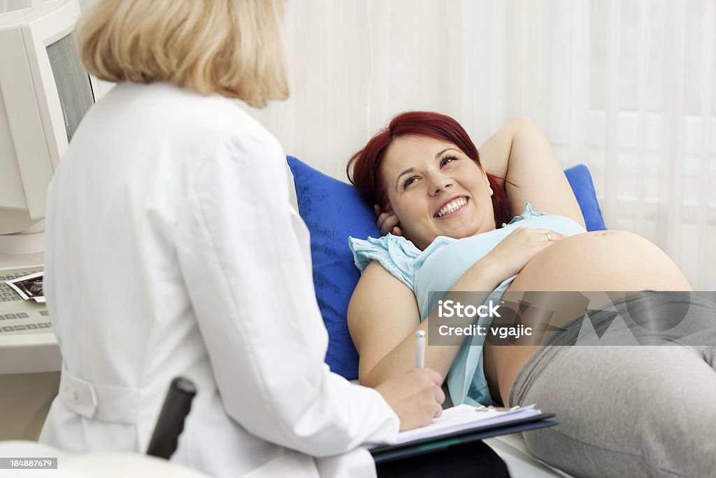 Pregnant Woman Answering Questions to Female Doctor Gynecologist Pregnant Woman Having An Ultrasound at doctor's office, female gynecologist taking notes and talking with pregnant woman, selective focus to pregnant woman Pregnant Stock Photo