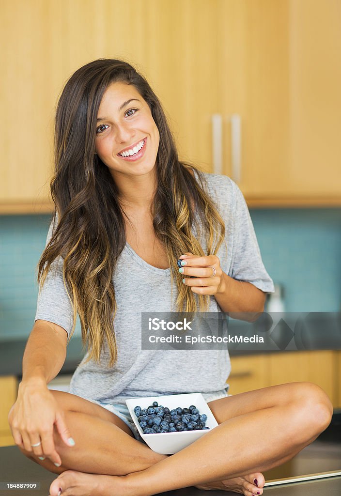 Woman With Bowl of Blueberries Portrait of beautiful young woman eating a bowl of blueberries and smiling Blueberry Stock Photo