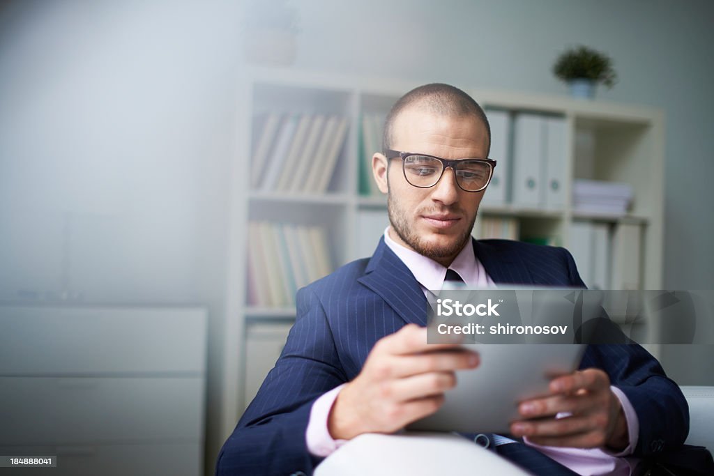 Man using tablet in office setting Portrait of businessman with touchpad working in office Adult Stock Photo